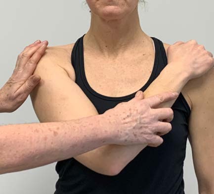 Patient som placerar handen på motsatta sidans axel.